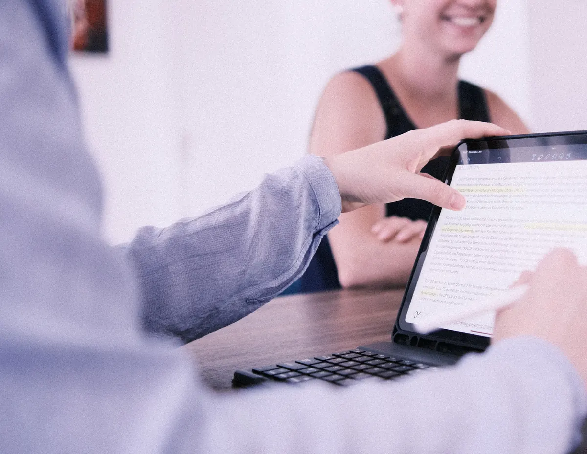 Eine Person sitzt vor einem Tablet mit Tastatur und arbeitet daran.